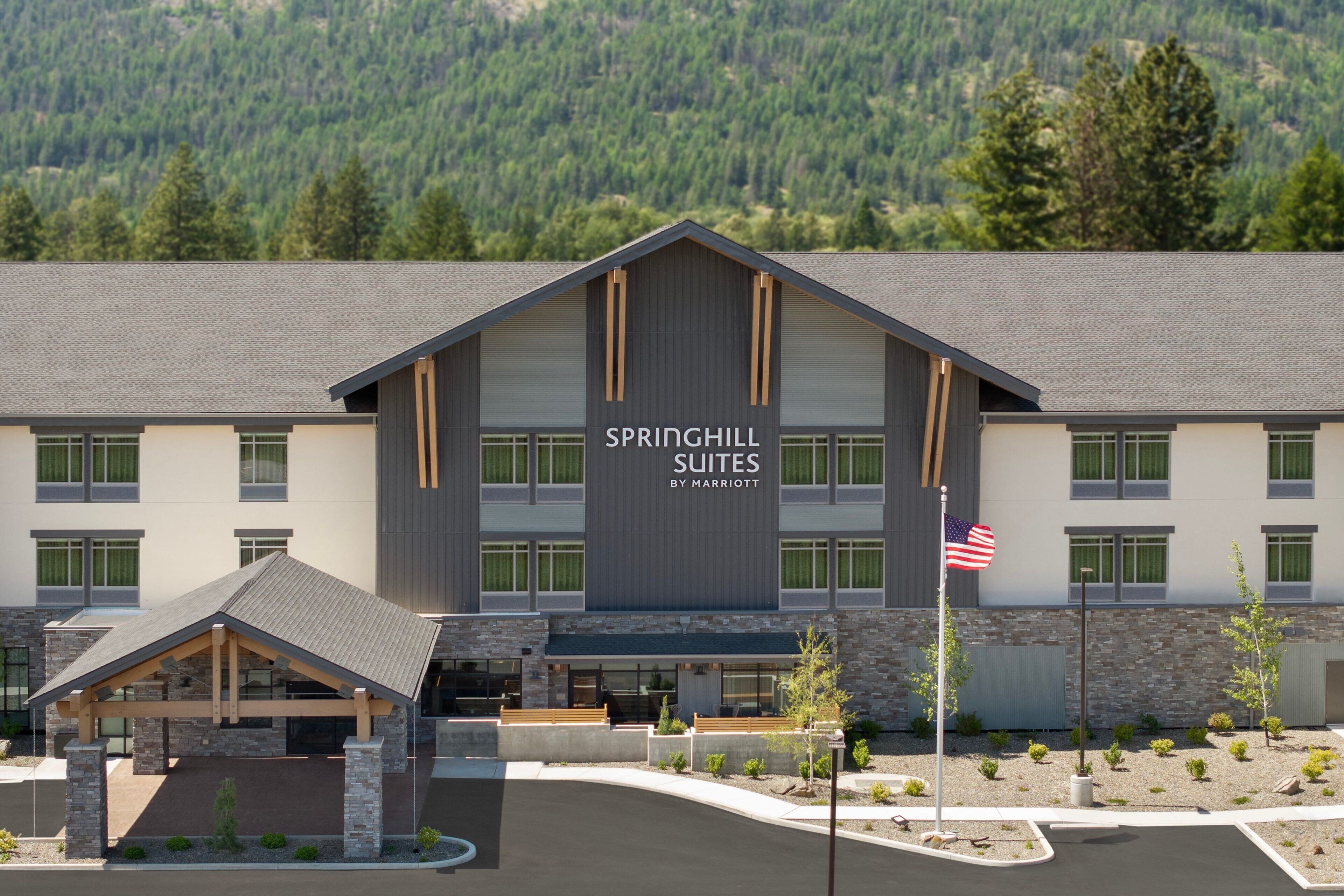 A modern hotel with a large sign reading "SPRINGHILL SUITES BY MARRIOTT" and a flagpole with an American flag.
