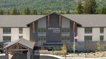 A modern hotel with a large sign reading "SPRINGHILL SUITES BY MARRIOTT" and a flagpole with an American flag.