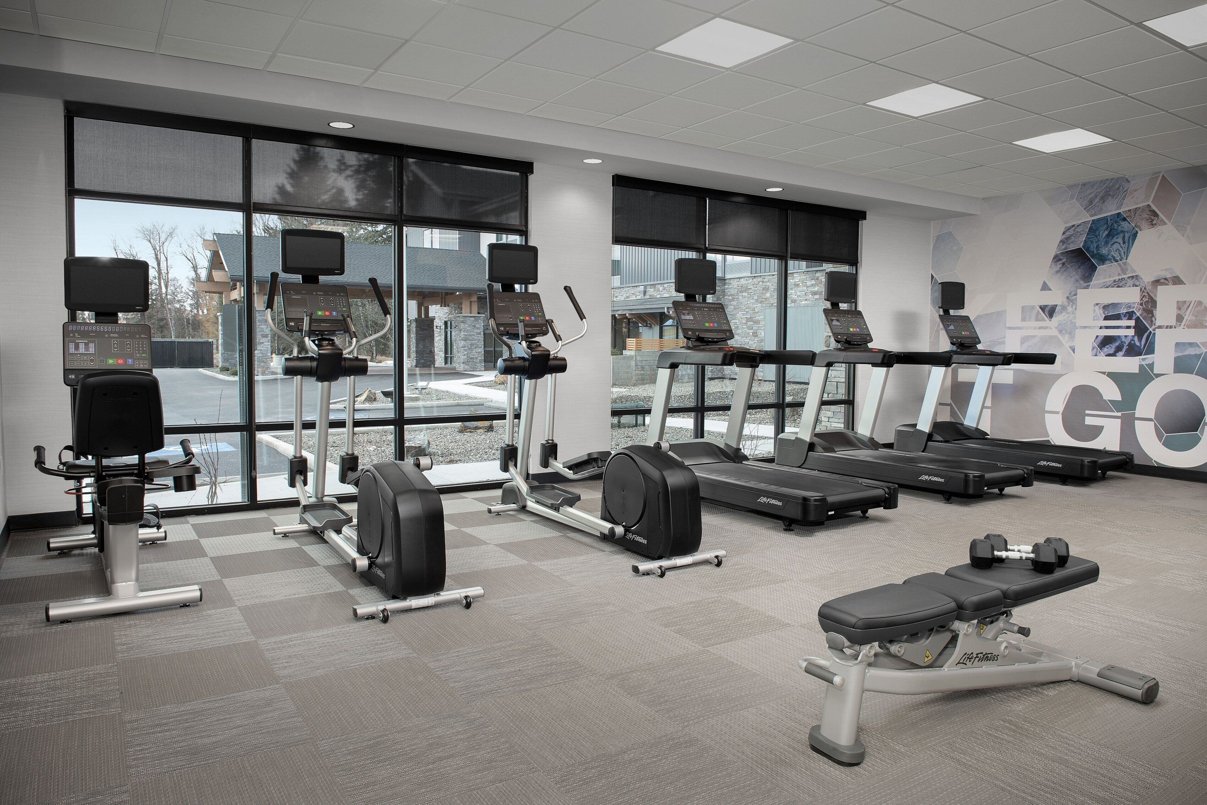 A gym with treadmills, elliptical machines, and weight benches.