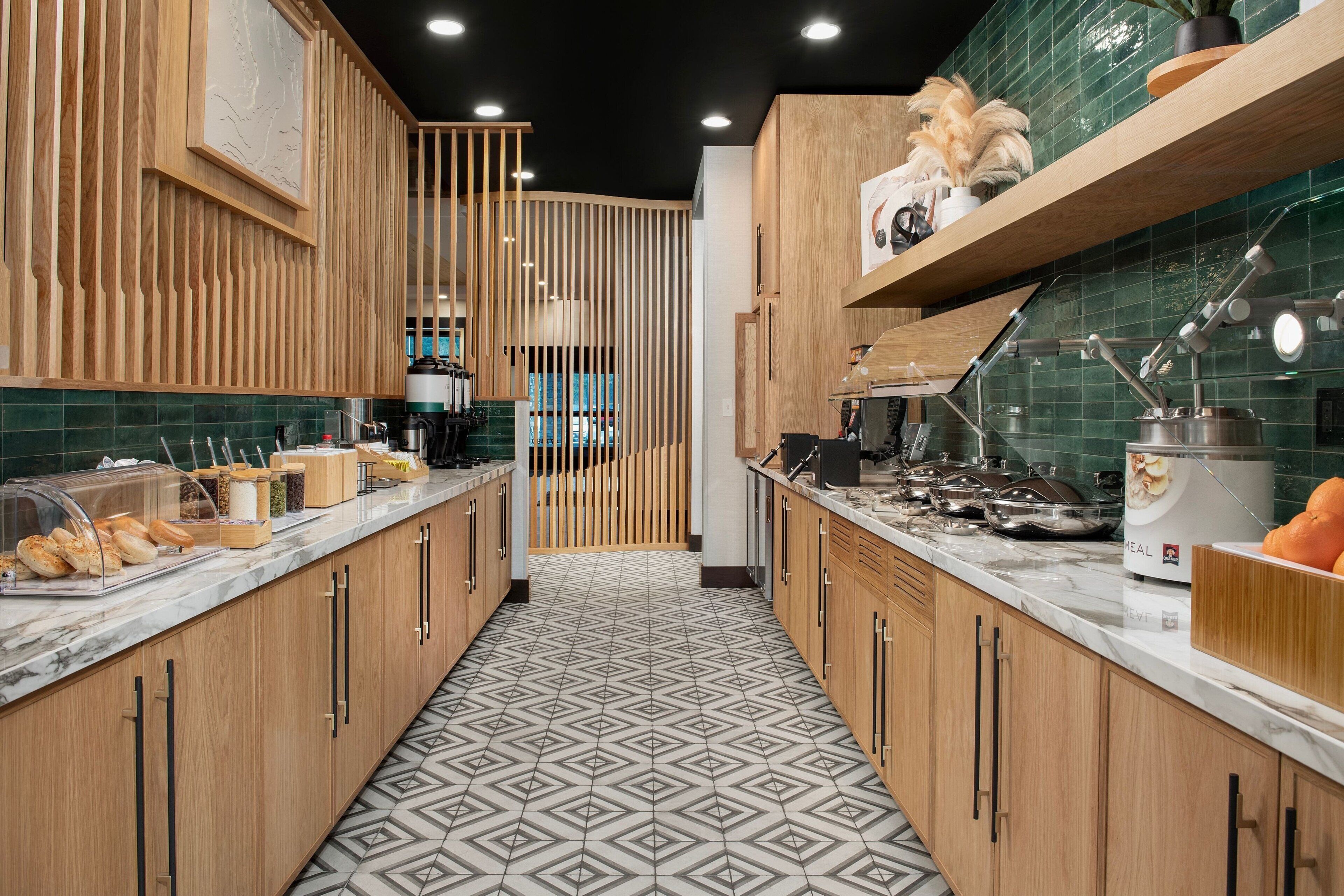 Une cuisine moderne avec des meubles en bois, un plan de travail en marbre et un sol à motifs.