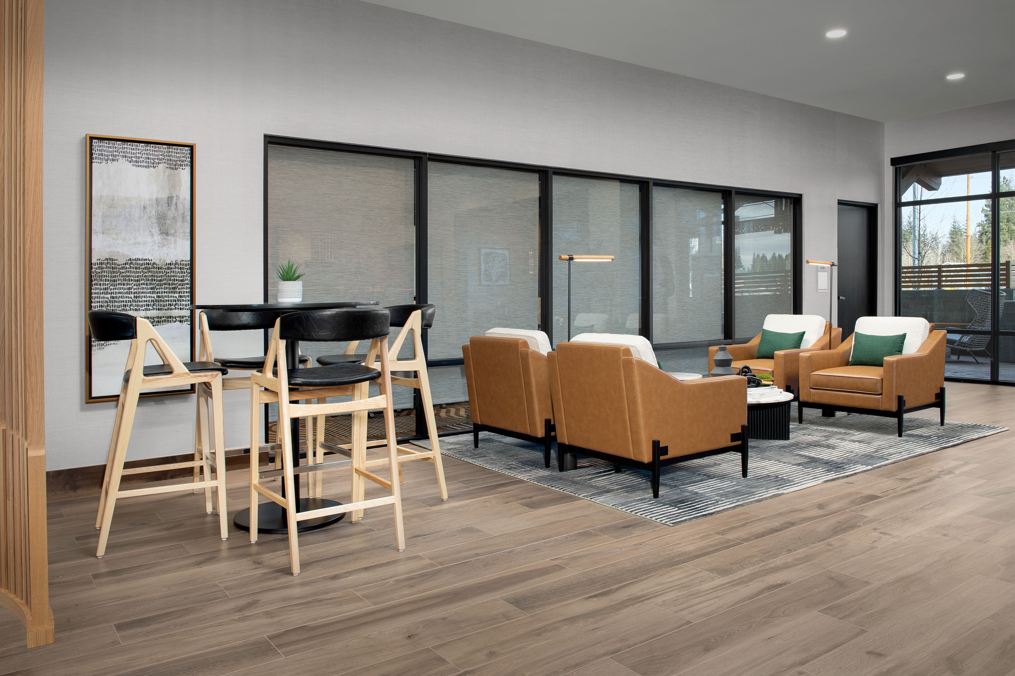 Un salon moderne avec un plancher en bois, un coin repas avec une table et des chaises noires, et un espace détente avec deux canapés et une table basse.