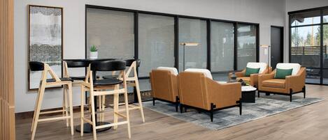 Un salon moderne avec un plancher en bois, un coin repas avec une table et des chaises noires, et un espace détente avec deux canapés et une table basse.