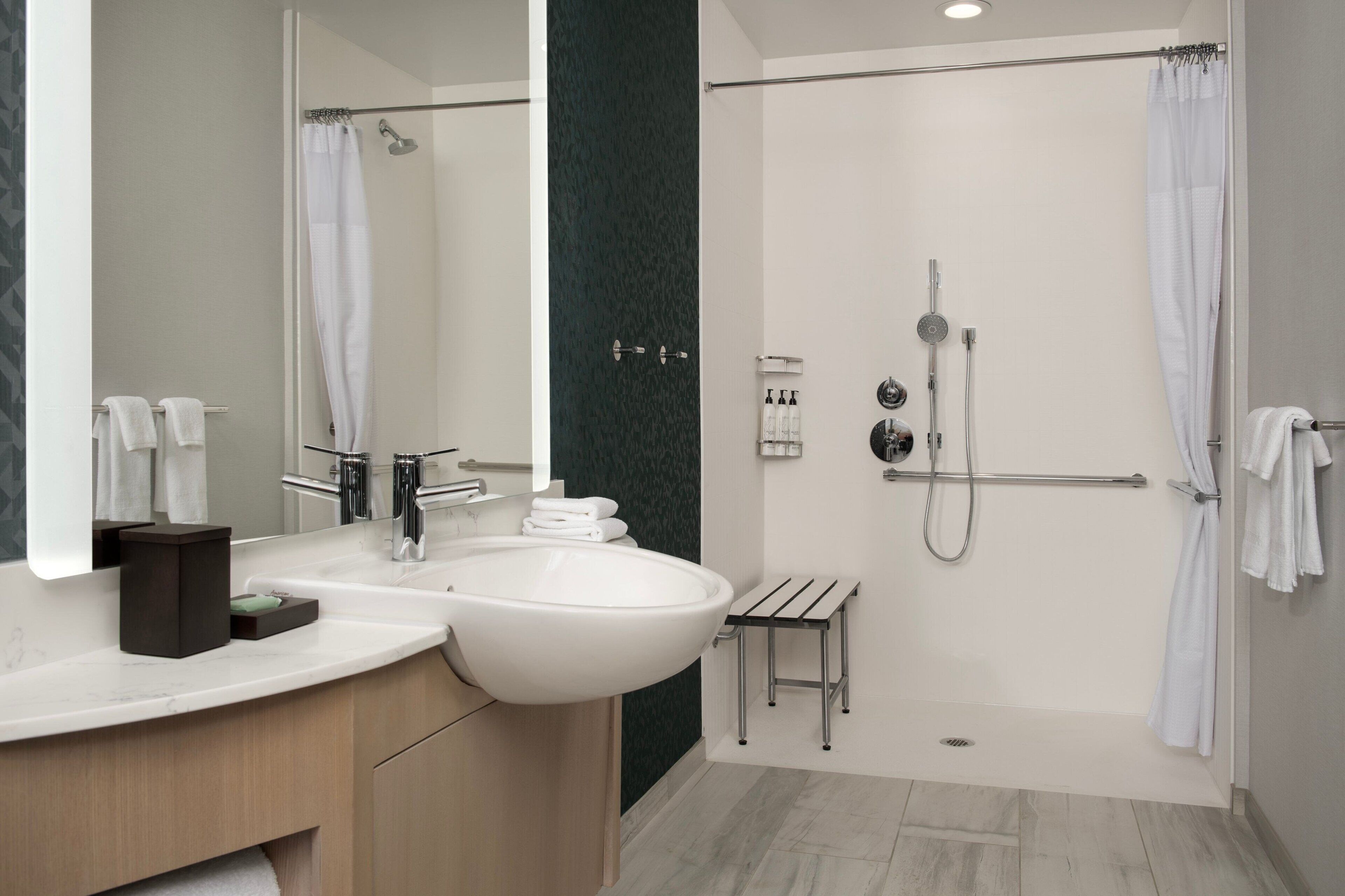 A modern bathroom with a large sink, mirror, and shower.