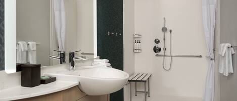 A modern bathroom with a large sink, mirror, and shower.