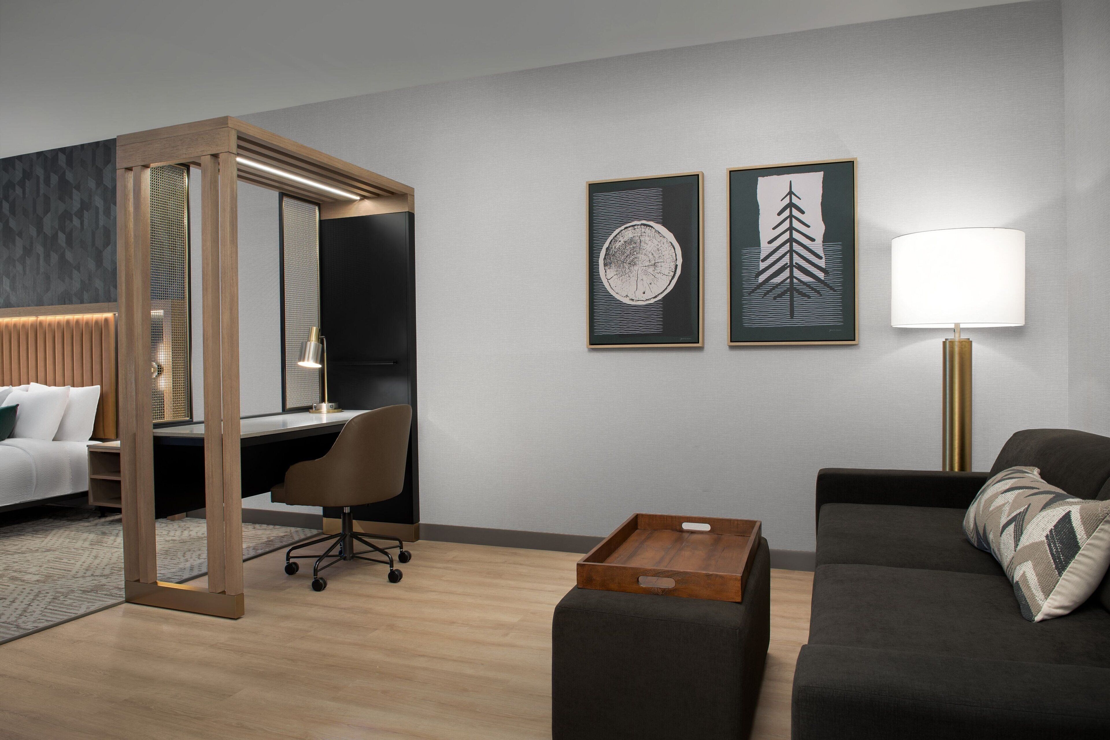 A modern hotel room with a bed, desk, and seating area.