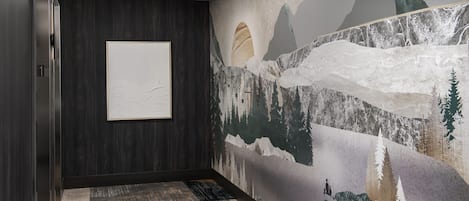 Ein Flur mit einer Wand aus dunklem Holz, einem gerahmten Kunstwerk und einem Wandbild mit einer Berglandschaft.