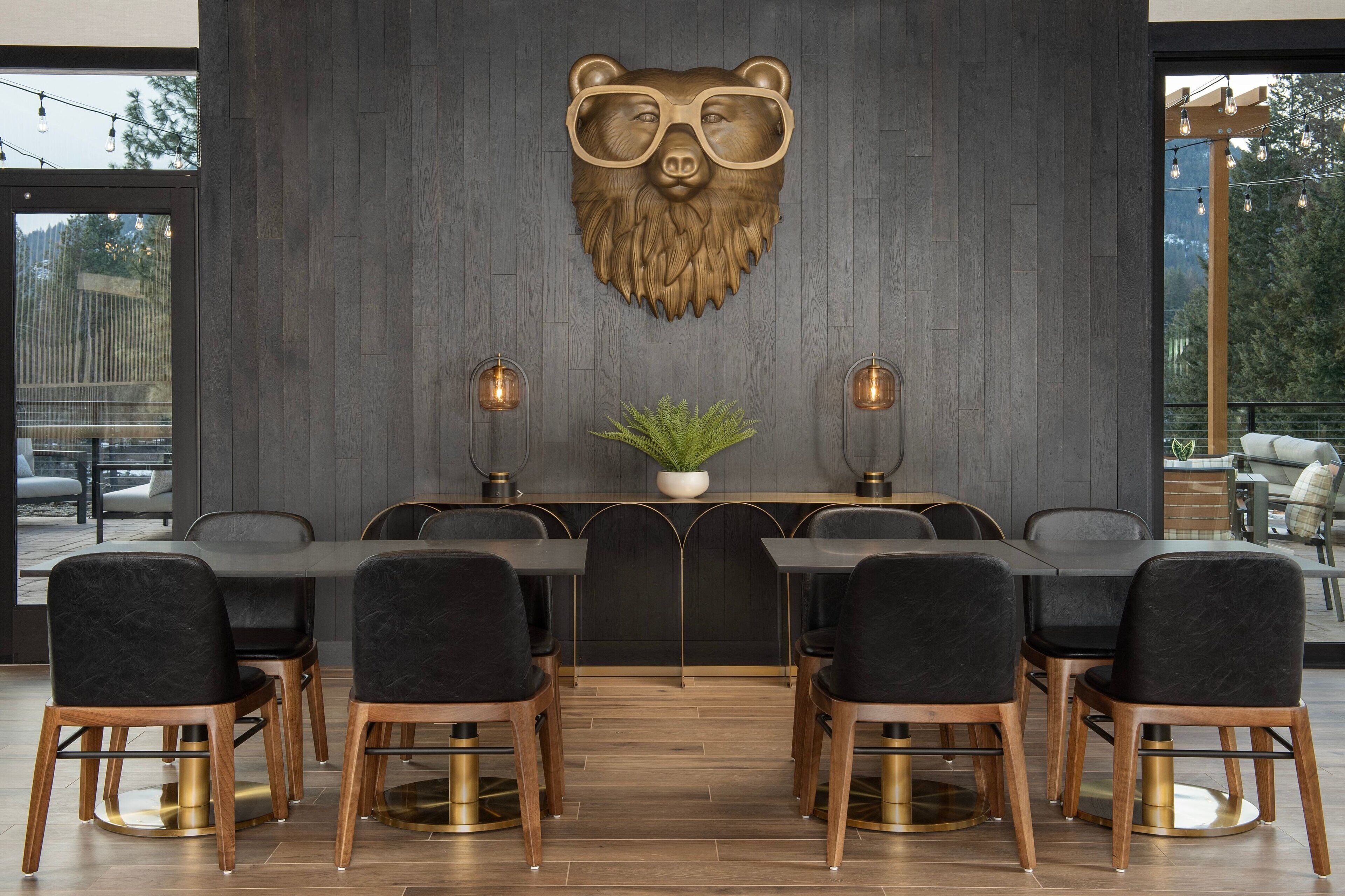 A modern dining area with a bear head wall art, a central plant, and a view of the outdoors.