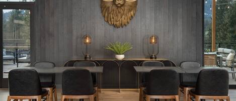 A modern dining area with a bear head wall art, a central plant, and a view of the outdoors.