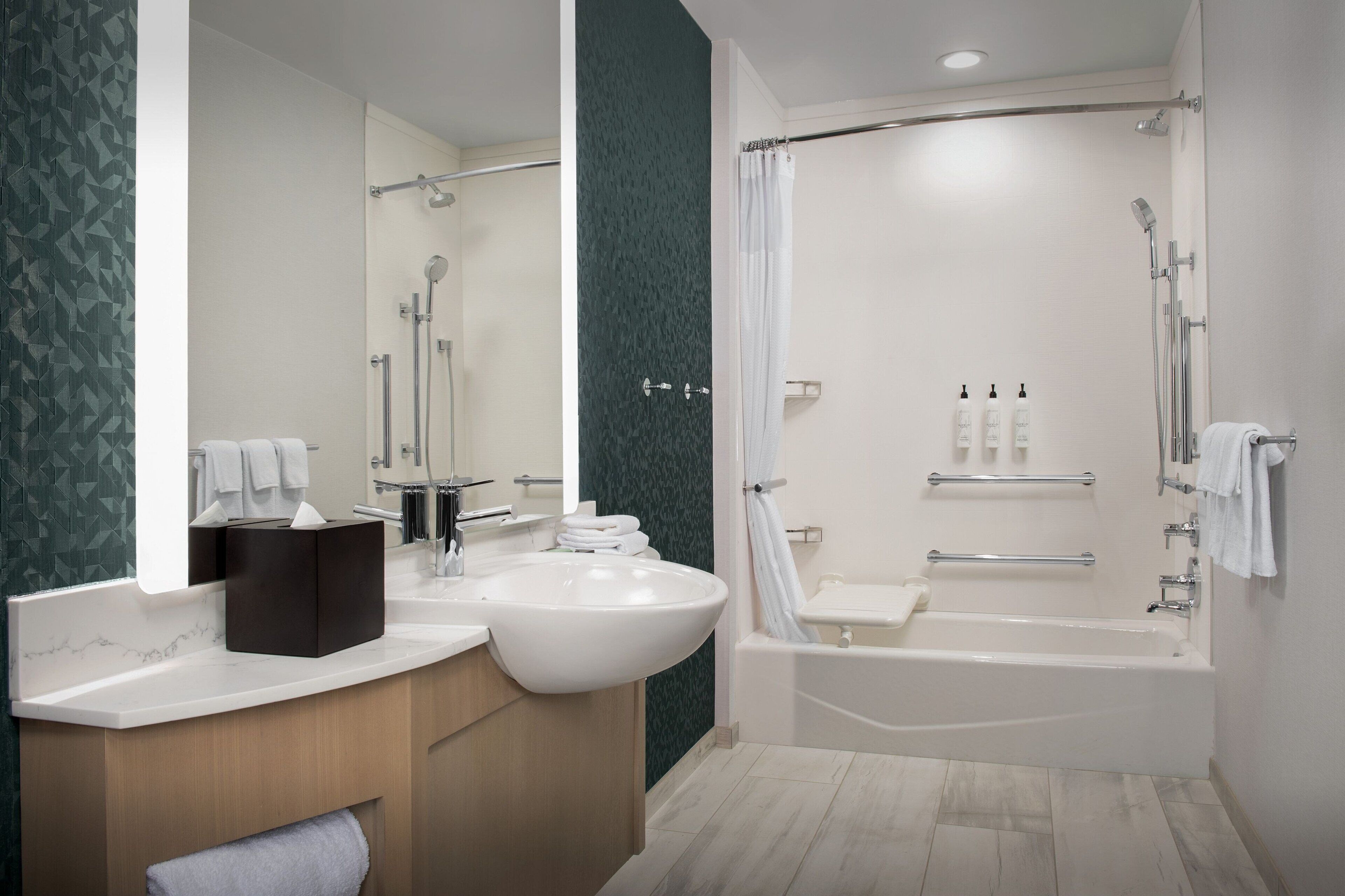 A modern bathroom with a large sink, mirror, and shower area.