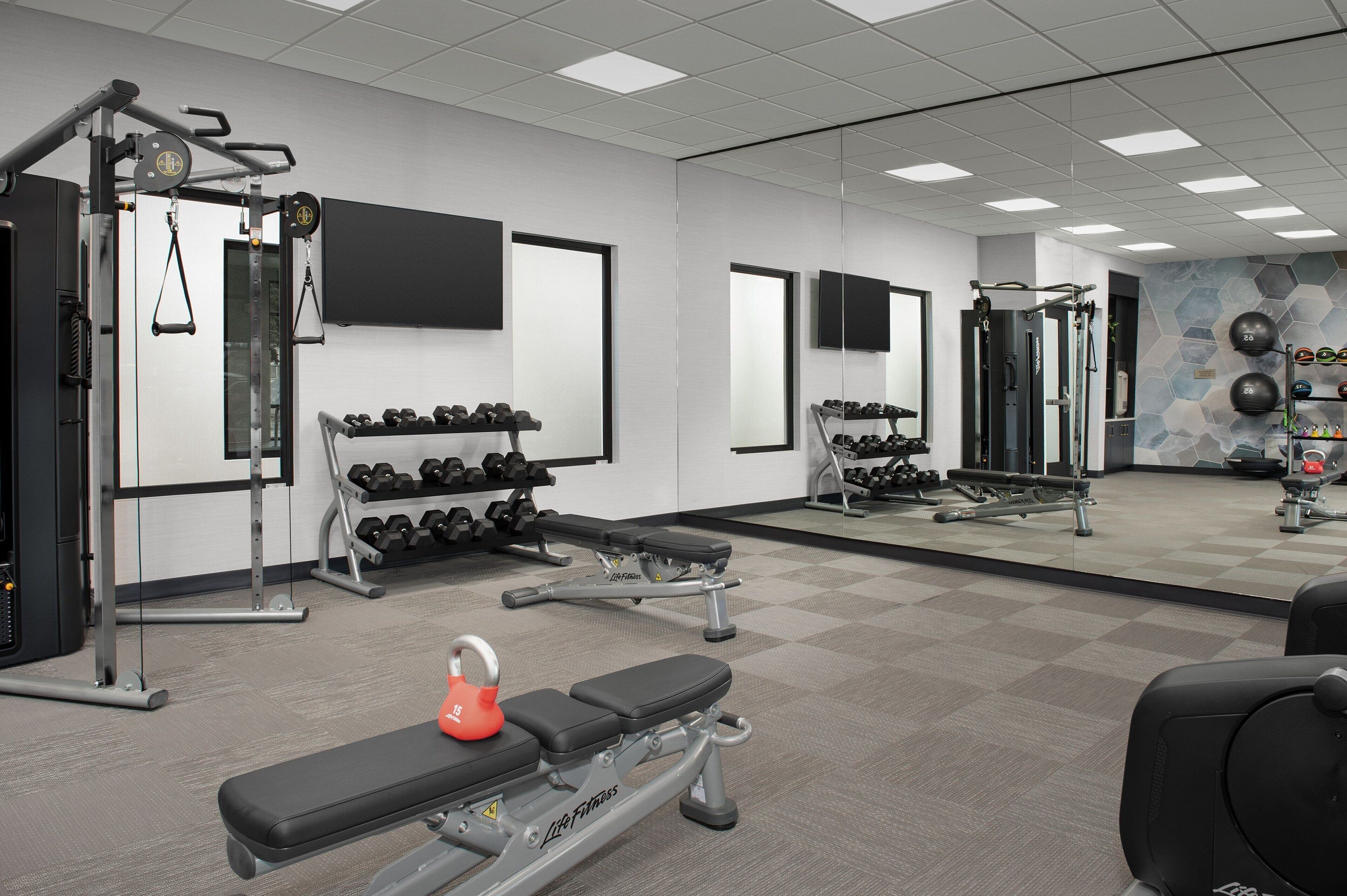 A gym with weightlifting equipment, dumbbells, and exercise machines.