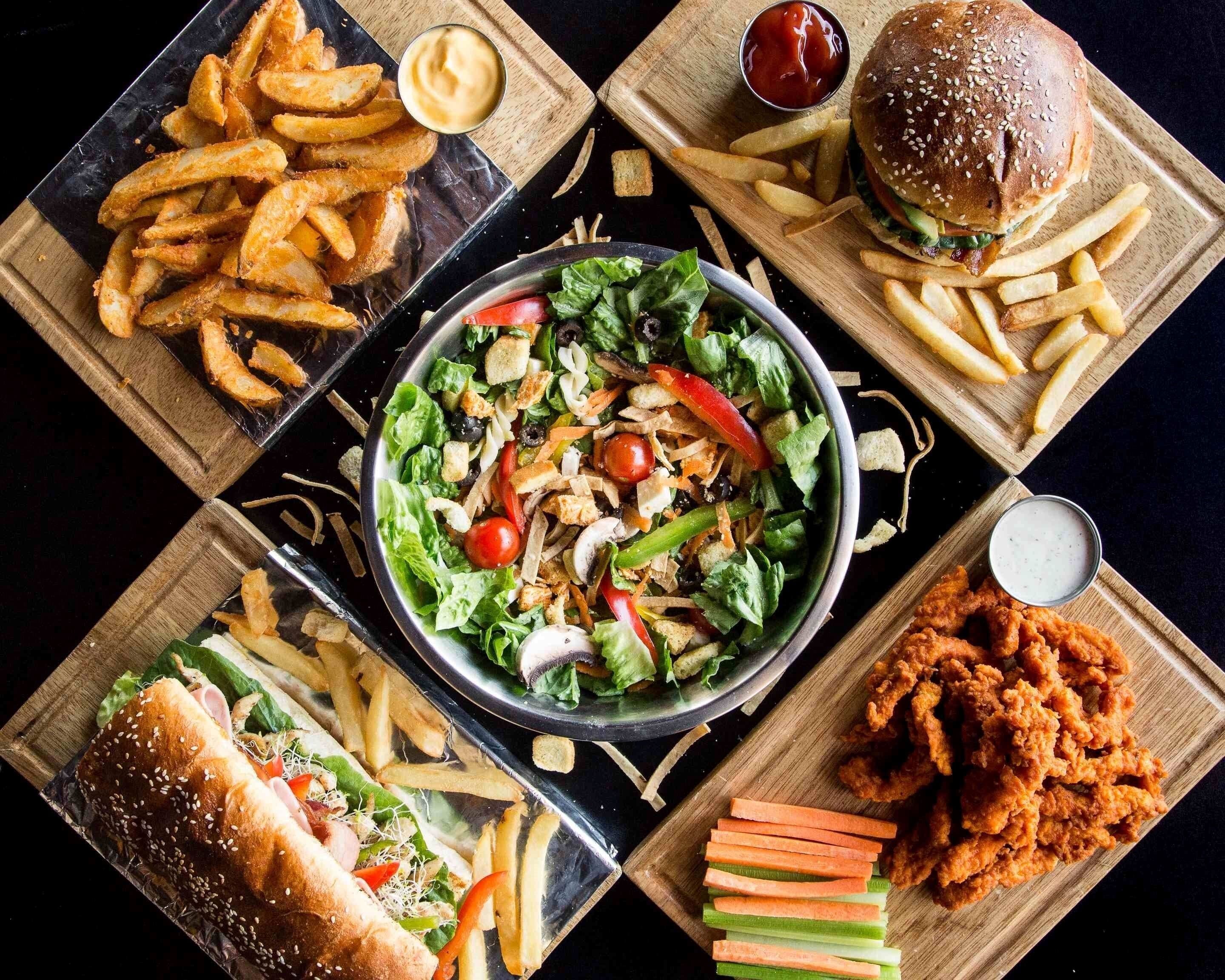 A meal with a burger, fries, salad, and chicken wings.