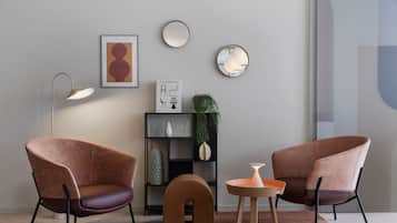 Una sala moderna con dos sillones marrones, una lámpara de pie, una mesita y una estantería con objetos decorativos.