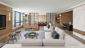 A modern living room with a large sofa, a coffee table, and a dining area with a table and chairs. - Sheraton Pujiang (Jinhua)