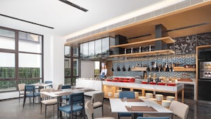 A modern restaurant with a bar area, large windows, and a chef preparing food. - Fairfield By Marriott Yangzhou Slender West Lake (Yangzhou)