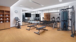 A modern gym with exercise equipment, a mirrored wall, and a wooden floor. - Fairfield By Marriott Yangzhou Slender West Lake (Yangzhou)