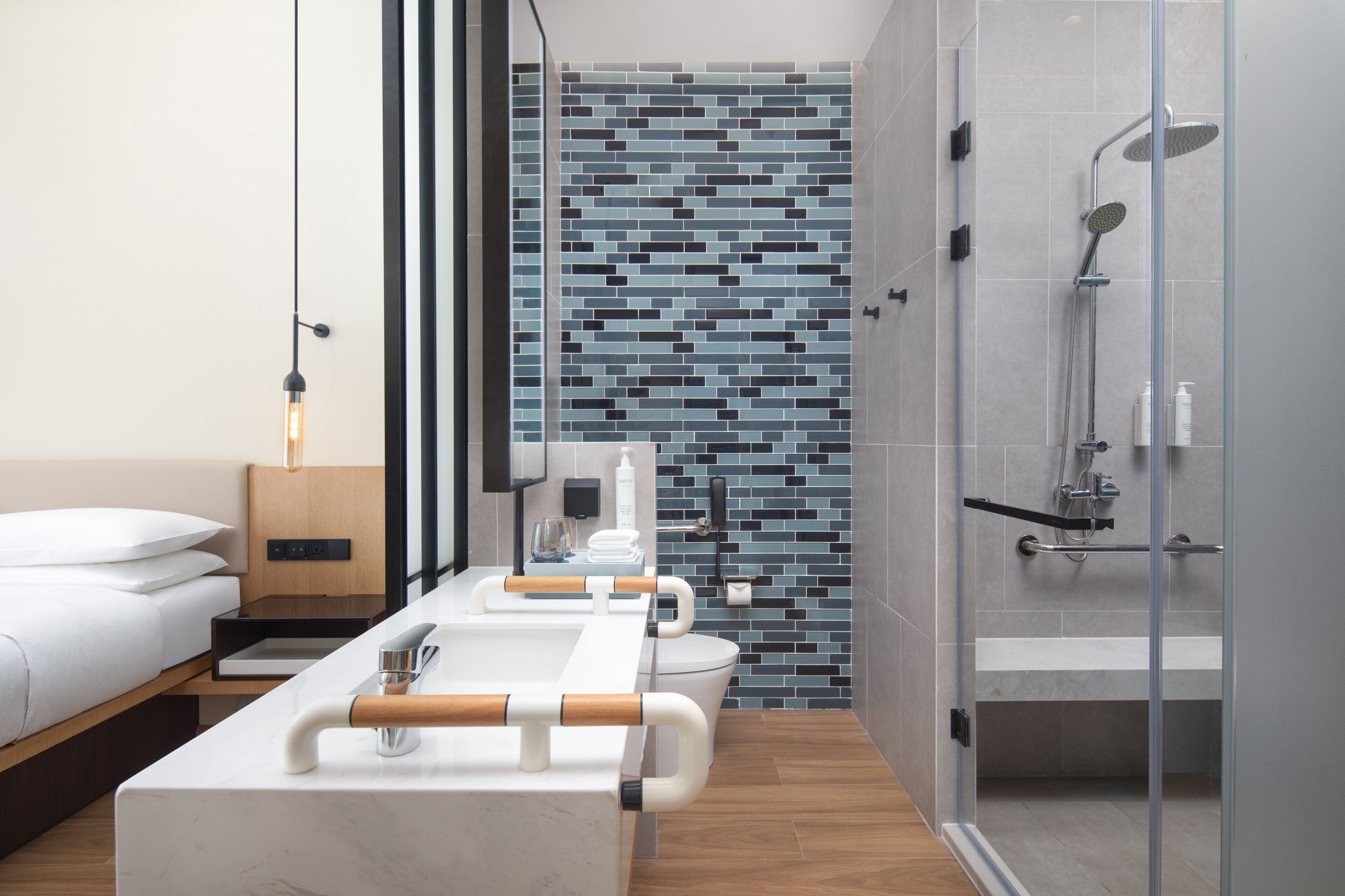 Une salle de bain moderne équipée d’une douche, de toilettes et d’un grand miroir.