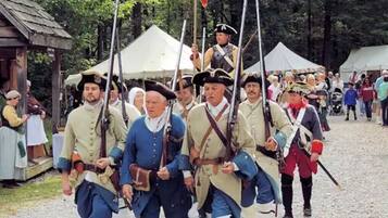 Un groupe de personnes vêtues de costumes d’époque marchant en file, probablement lors d’une reconstitution historique.