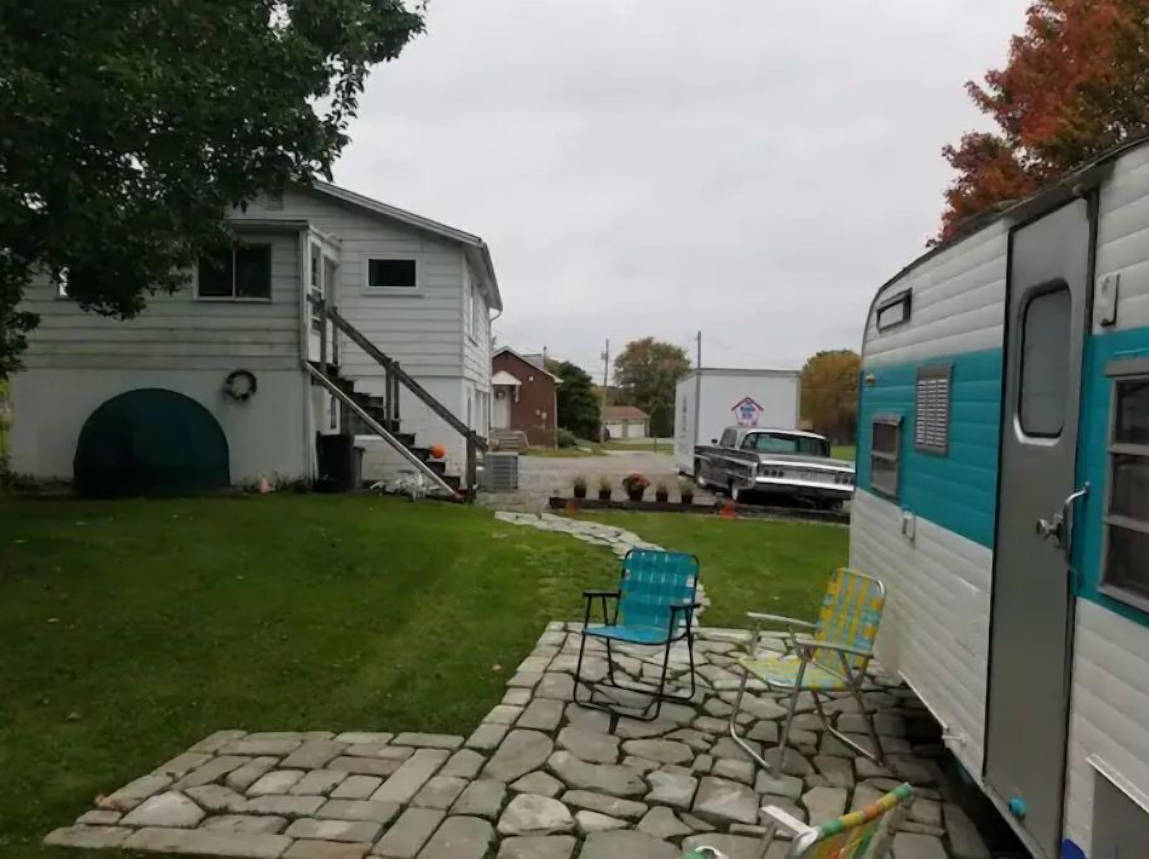 Et boligområde med et hvidt hus, en carport og en campingvogn.