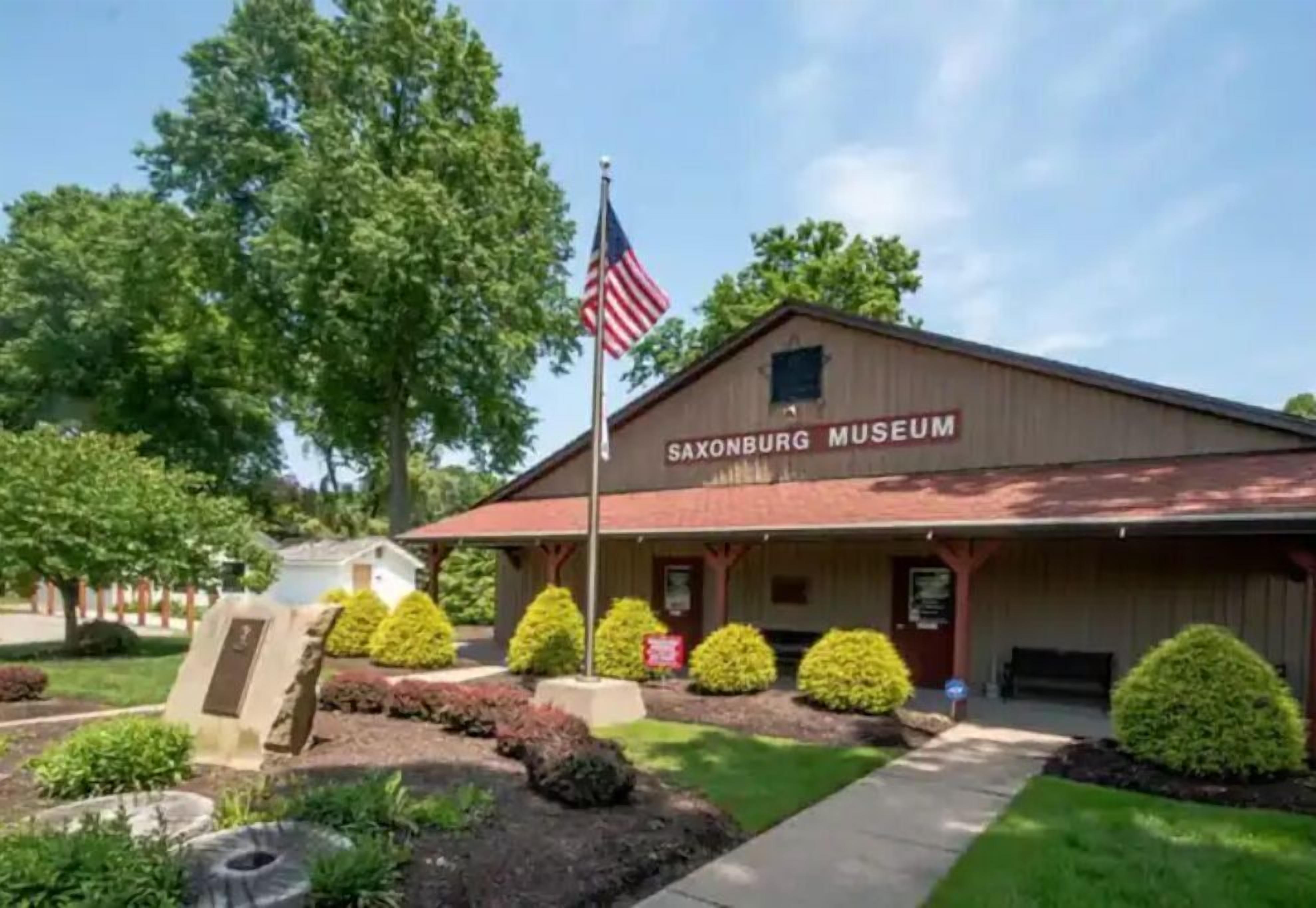 The Saxonburg Museum building with a flagpole, a sign, and well-maintained landscaping.