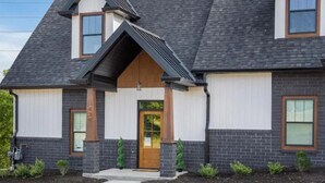 A two-story building with a dark roof, white exterior walls, and a central entrance with a wooden door. - Spacious Smoky Mountain Retreat in Sevierville (Sevierville)