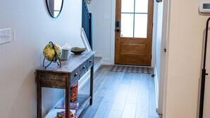 A hallway with a wooden floor, a console table with a globe, a mirror, and a door at the end. - Spacious Smoky Mountain Retreat in Sevierville (Sevierville)
