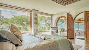 Ein Schlafzimmer mit einem großen Bett, einem Sessel und Blick ins Freie.