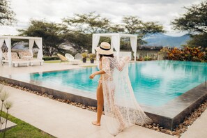 A poolside area with a person in a white dress and hat, a white gazebo, and a view of trees and mountains in the background. - Tunas & Cabras Hotel  (Ibarra)