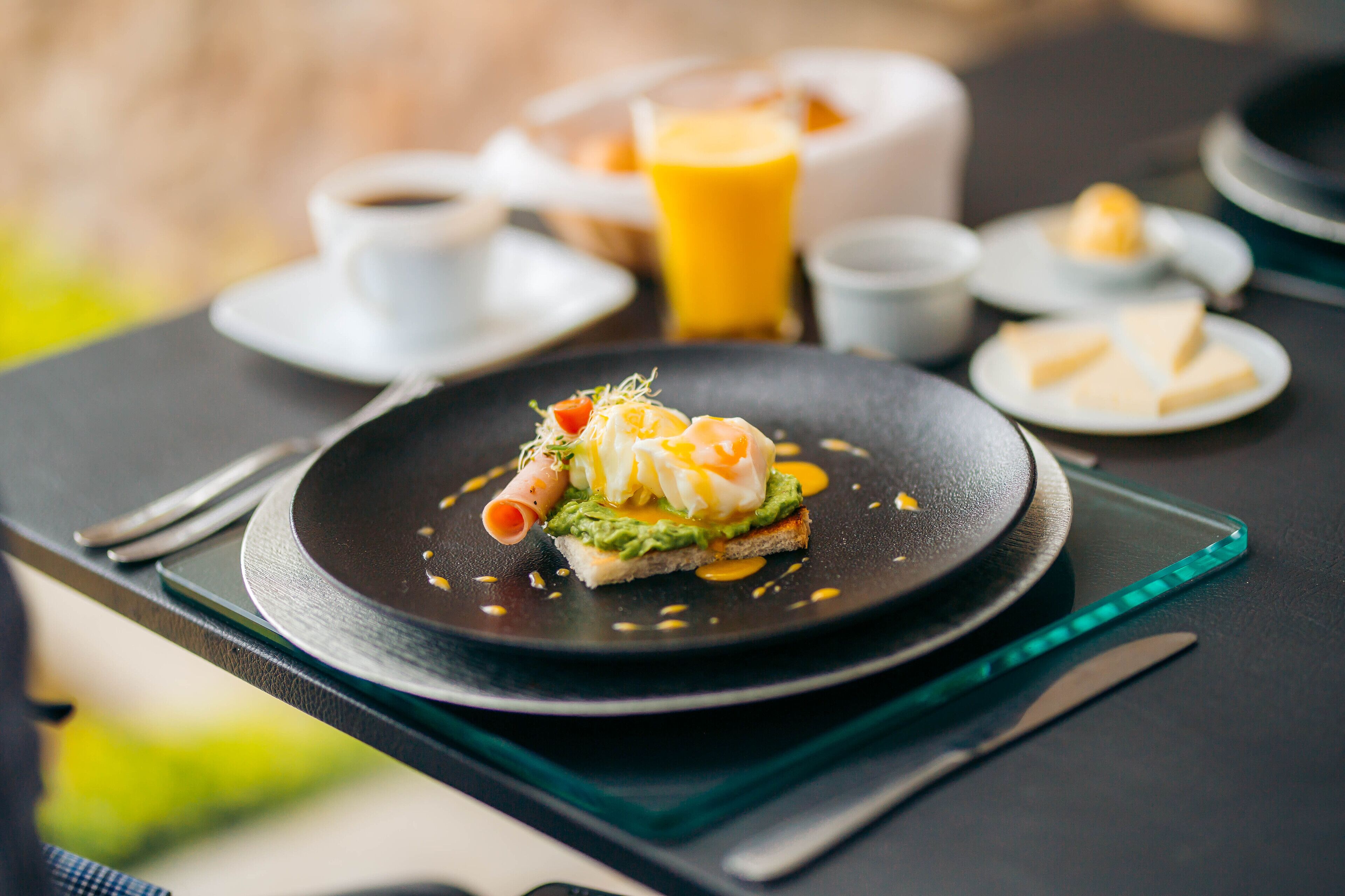 Un desayuno con un plato de comida, una taza de café y un vaso de zumo de naranja sobre una mesa.
