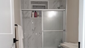 A bathroom with a toilet, a shower, and a sink.