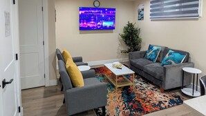 A modern living room with a grey sofa, a coffee table, and a TV mounted on the wall.