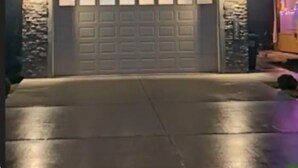 A two-story house with a garage, stone facade, and a driveway.