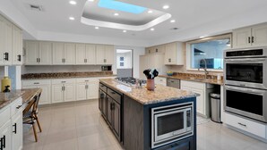 A modern kitchen with white cabinets, granite countertops, and stainless steel appliances. - Fun-for-all! Pool! Private Pickleball Court! Game room! (Tucson)