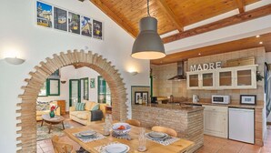 A cozy interior with a dining area, a kitchen with a 'MADRE' sign, and a brick archway. - Charming Rural Retreat, A/C, Private Pool & Beautiful Views - 11km from the Coastal Town of Tavira! (Tavira)