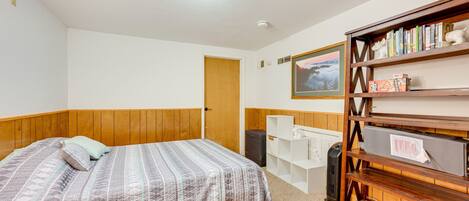 A bedroom with a bed, a bookshelf, a radiator, and a door.