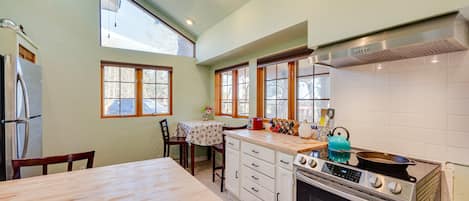 A kitchen with a wooden table, a stove, and a ceiling fan.