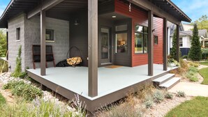 Una casa moderna con un porche cubierto, fachada de piedra y sección de revestimiento rojo.
