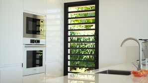 A modern kitchen with a Bosch microwave, oven, and a black-framed window with greenery. - Modern villa ZYX with private pool, open-air cinema and 180° sea view (Saint-François)