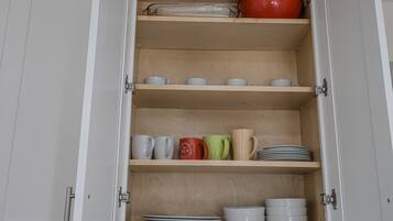 Un mueble con varios estantes que contiene platos y tazas.