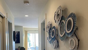 A hallway with wooden flooring, a wall-mounted mirror, and a door leading to a living area. - The Spot on Sproat Lake (Port Alberni)