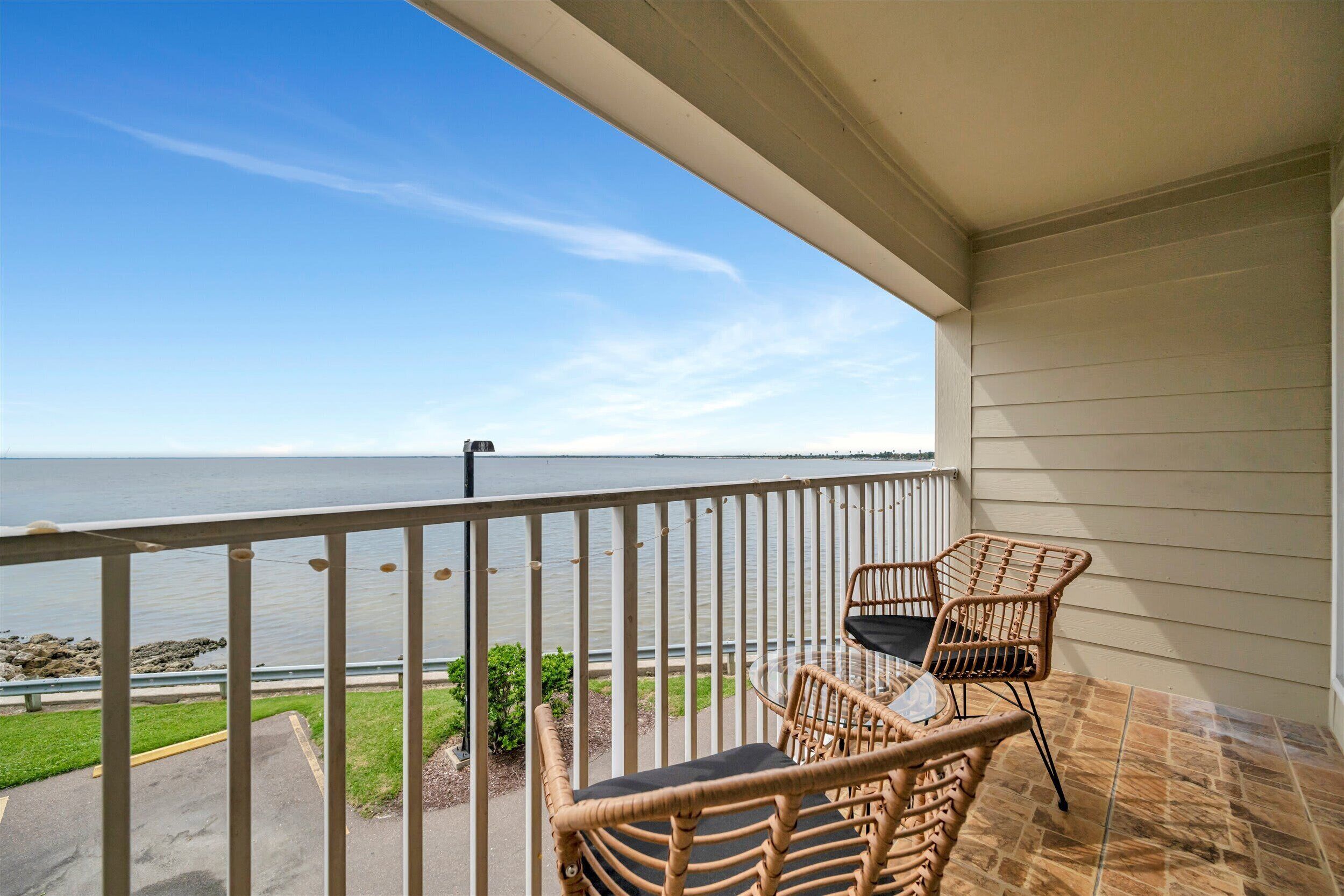 A balcony with wicker chairs and a view of the water.