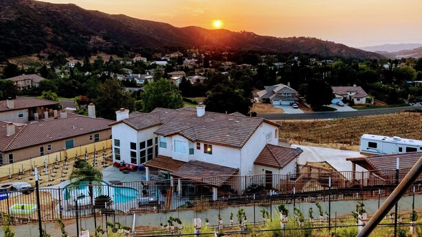 Zona residencial con casas, una piscina y un paisaje montañoso al fondo.