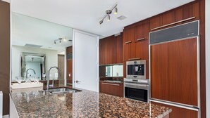 A modern kitchen with granite countertops, stainless steel appliances, and wooden cabinetry.