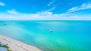 A beach with a clear blue sky, turquoise water, and a boat.