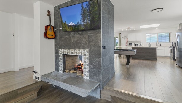 Una cocina moderna con chimenea empotrada, un televisor de pantalla plana montado encima y una guitarra apoyada contra la pared.