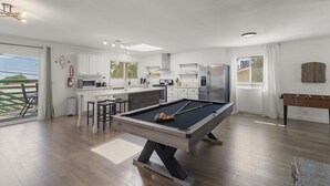 Una cocina moderna con mesa de billar, taburetes de bar y mesa de fútbolín.