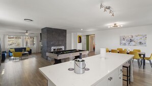Amplia sala de estar con mesa de billar, sofá y mesa de comedor con sillas amarillas.