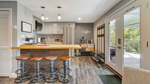 A modern kitchen with a bar area, wooden stools, and a coffee sign. - Stratton; 8 min! Fire Pit. BBQ. Pet friendly (Winhall)
