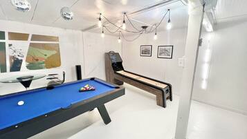 A pool table with a blue felt surface, a billiards cue rack, and a disco ball hanging from the ceiling.