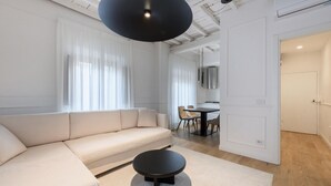 Una sala de estar moderna con un sofá, una mesa de centro redonda y un comedor con sillas y una mesa.