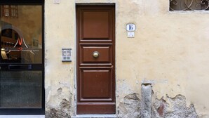 Una puerta marrón con una placa que indica el número 16 en una pared con textura.